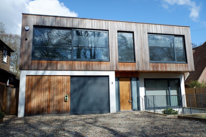 Modern two storey flat roofed house, clad with external cedar wood - stock photo