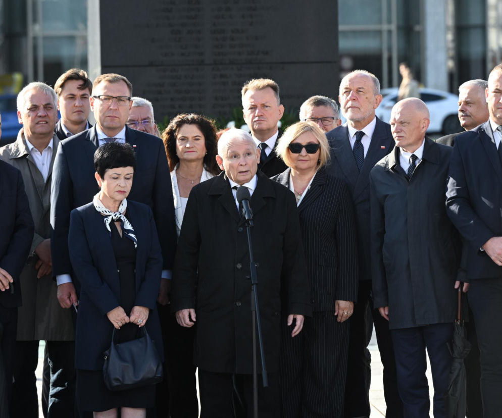 Jarosław Kaczyński przemawia do mikrofonu w otoczeniu polityków PiS. O miesięcznicy smoleńskiej przeczytasz na SE Polityka.