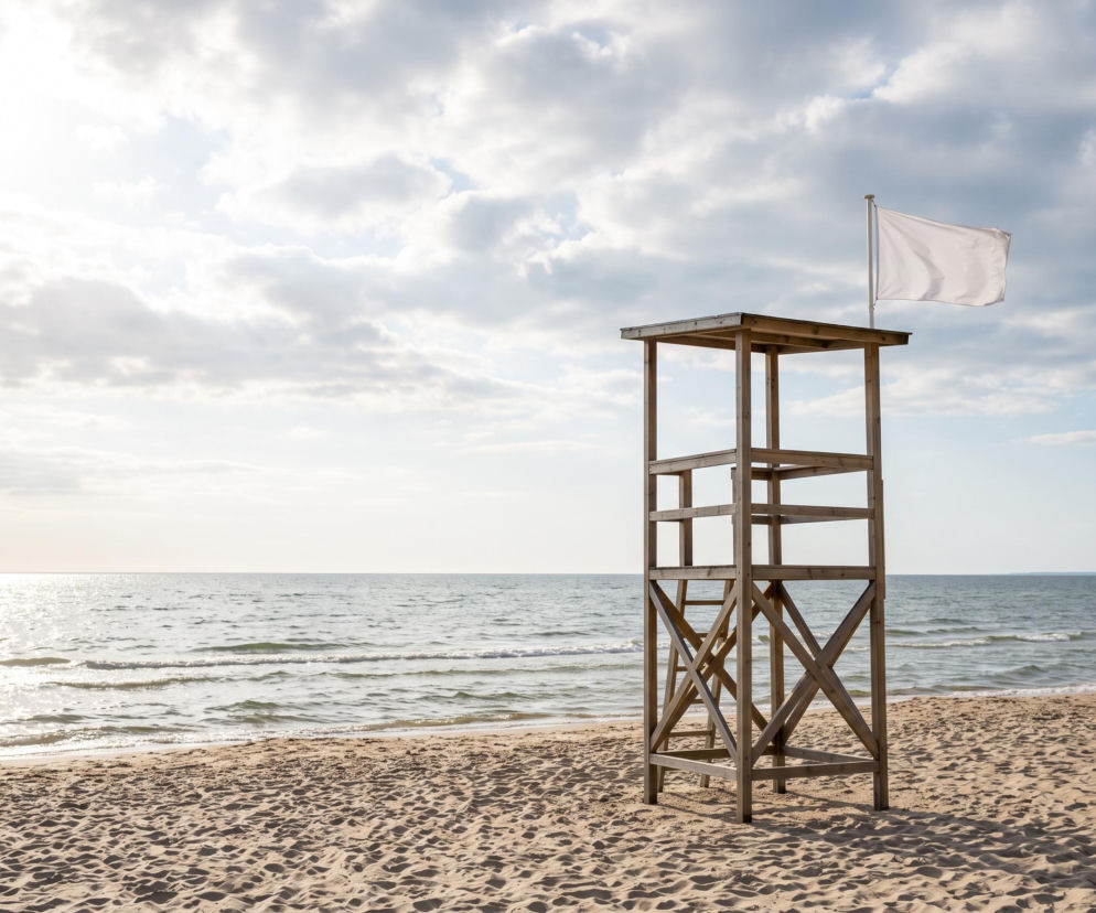 Drewniana wieża ratownika z białą flagą na plaży w Międzyzdrojach. O bezpieczeństwie nad wodą przeczytasz na SE Szczecin.