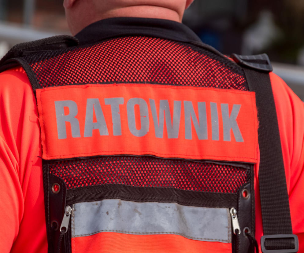 Plecy ratownika medycznego w pomarańczowym stroju z napisem Ratownik. O ataku w Przemyślu przeczytasz na SE.