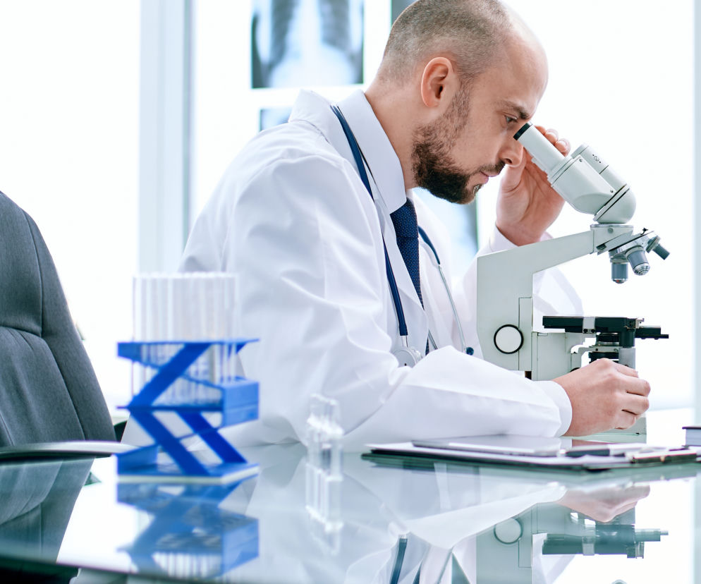 naukowiec badający próbkę pod mikroskopem