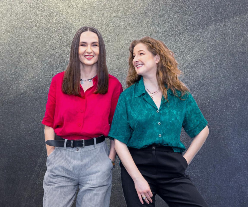 Kasia Pilewska i Sylwia Dominik z podcastu Odkrywczynie Znaczeń na tle ciemnej ściany. O tańcu przeczytasz na Mediateka.