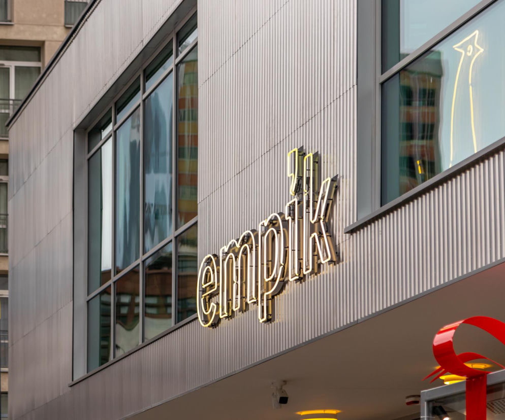 Złoty neon z napisem Empik na nowoczesnym budynku. O ofercie plecaków ewakuacyjnych w sieci przeczytasz na SE.