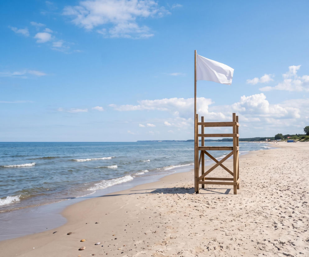 Drewniana wieżyczka ratownicza z białą flagą na plaży w Sarbinowie. O bezpieczeństwie kąpieli dowiesz się w SE Szczecin.