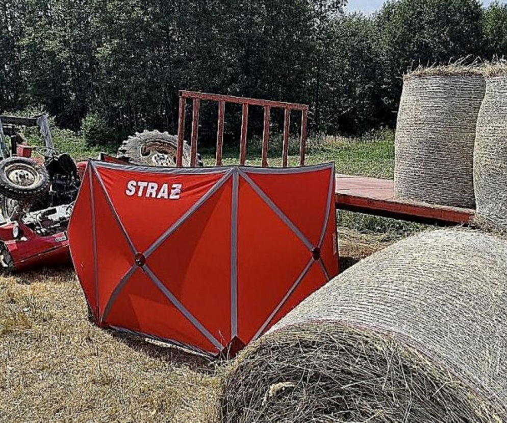 Przewrócony ciągnik i parawan strażacki na polu obok bel siana. O wypadku w Kikowie przeczytasz na Eska Kielce.