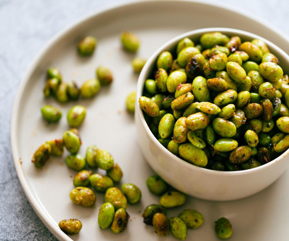 Miska z przypieczonymi ziarnami edamame na jasnym talerzu. O tej zdrowej przekąsce na cholesterol przeczytasz na PZ Fit.