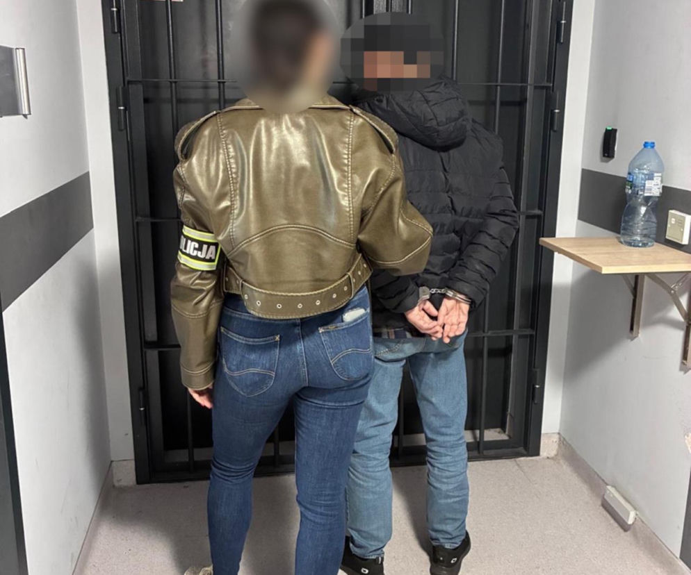 Policjantka prowadzi zakutego w kajdanki 71-latka przed kratę. O zatrzymaniu złodzieja z Mokotowa przeczytasz na SE.