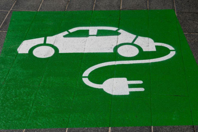 Znak miejsca do ładowania aut elektrycznych na zielonym tle. O tanich modelach przeczytasz na EskaRock.