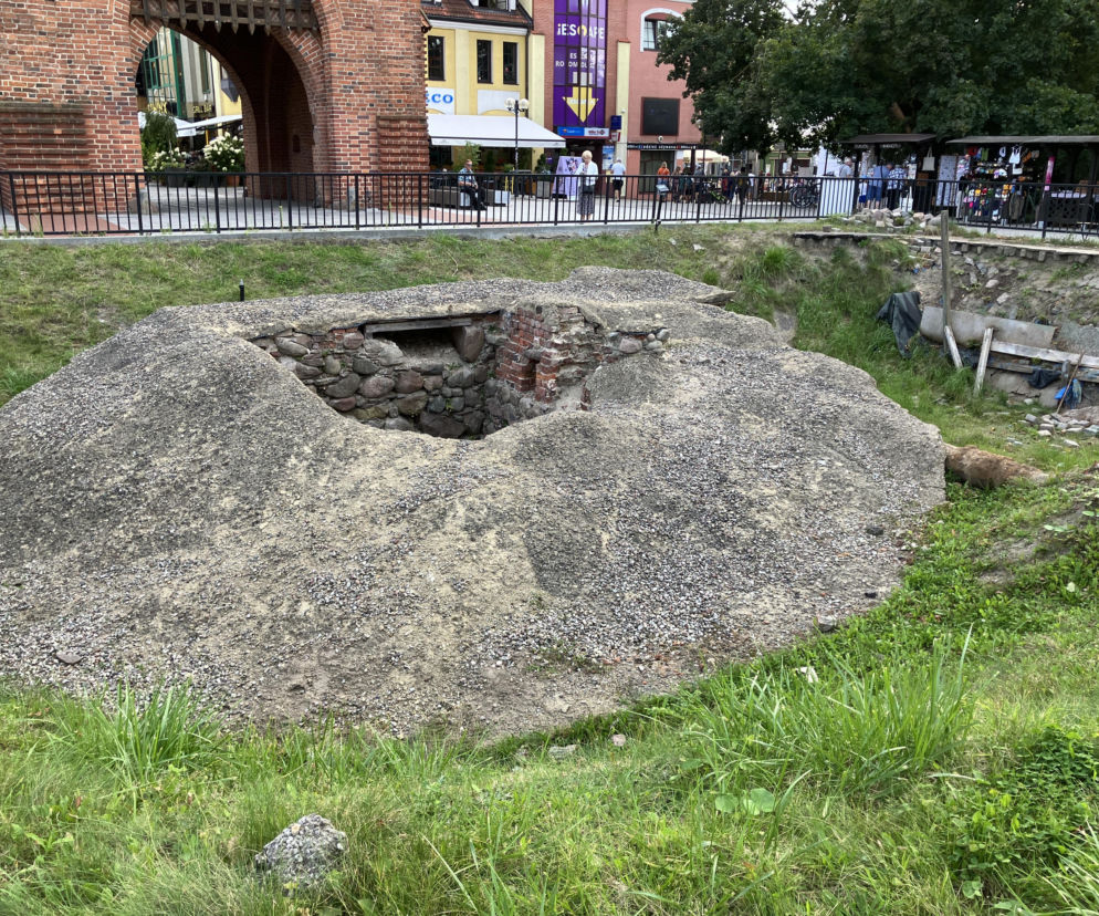 Odkryte fundamenty średniowiecznej rondeli przy Wysokiej Bramie w Olsztynie, otoczone usypaną ziemią z kamieniami, ukazują problem wyeksponowania historycznych pozostałości w centrum miasta. Więcej o wyzwaniach projektowych w takich miejscach na Architektura Murator Plus.
