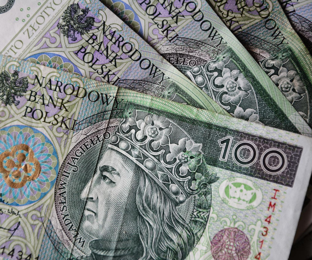 Stos banknotów o nominale 100 złotych, na których widać Władysława Jagiełłę, symbolizujący wzrost wynagrodzeń, ale i spadek liczby etatów w Polsce, o czym przeczytasz na Super Biznes.