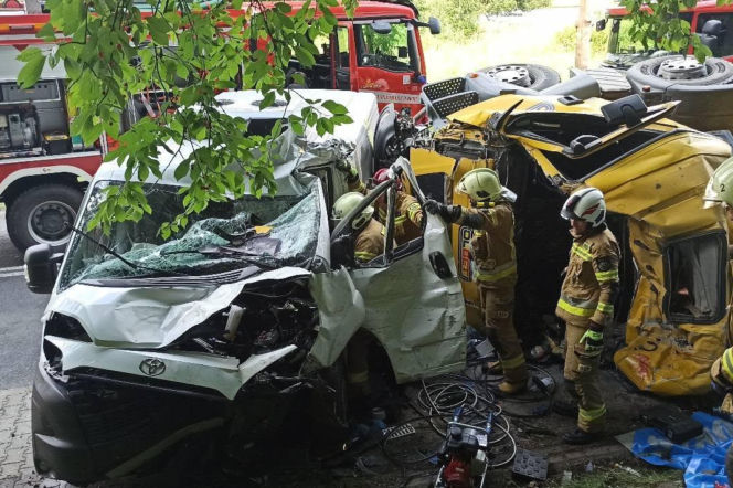 Strażacy pracują przy zmiażdżonym białym samochodzie i przewróconej betoniarce. O tragedii przeczytasz na Eska Śląskie.