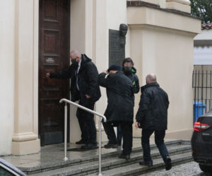 Pięciu ochroniarzy prowadzi Kaczyńskiego do bramy