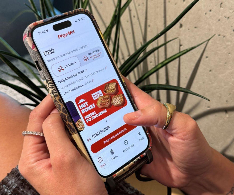 Ręce osoby obsługującej aplikację Pizza Hut na smartfonie. O nowościach technologicznych w AmRest przeczytasz na Eska.