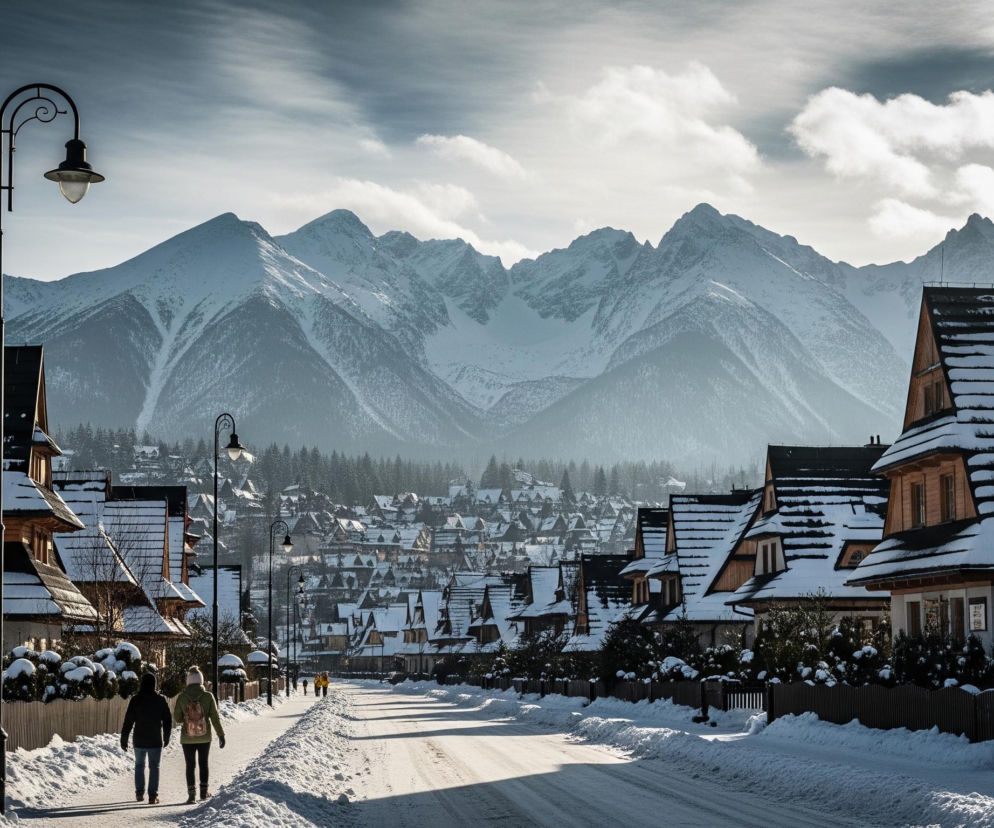 Zimowy krajobraz przedstawia zaśnieżoną ulicę w dolinie, otoczoną dwoma rzędami tradycyjnych drewnianych domów z ciemnymi dachami, również pokrytymi grubą warstwą śniegu. W tle rozciąga się majestatyczny łańcuch górski, którego szczyty spowija biel śniegu i mgła, a niebo nad nimi ozdobione jest rozproszonymi chmurami. Wzdłuż ulicy, na której zalega śnieg, widać kilka osób, w tym parę idącą w kierunku oddalonych, zaśnieżonych budynków, oraz pojedyncze postaci w tle. Czarne, ozdobne latarnie uliczne, stojące po lewej stronie drogi, oświetlają scenę.