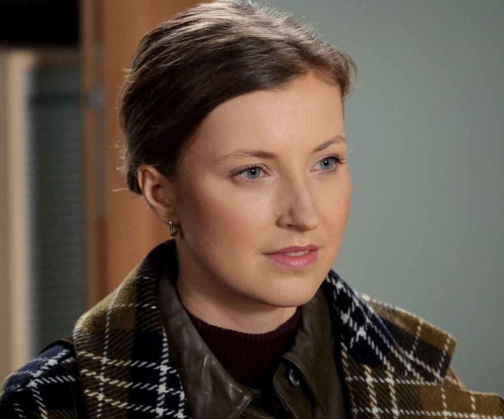 Portret Natalki Mostowiak z M jak miłość (Dominika Suchecka) w zbliżeniu, ukazujący jej zamyśloną minę i delikatny makijaż, ubraną w kraciastą kurtkę. Obraz odzwierciedla emocjonalny kontekst nadchodzących wydarzeń w serialu, o których przeczytasz na Super Seriale.