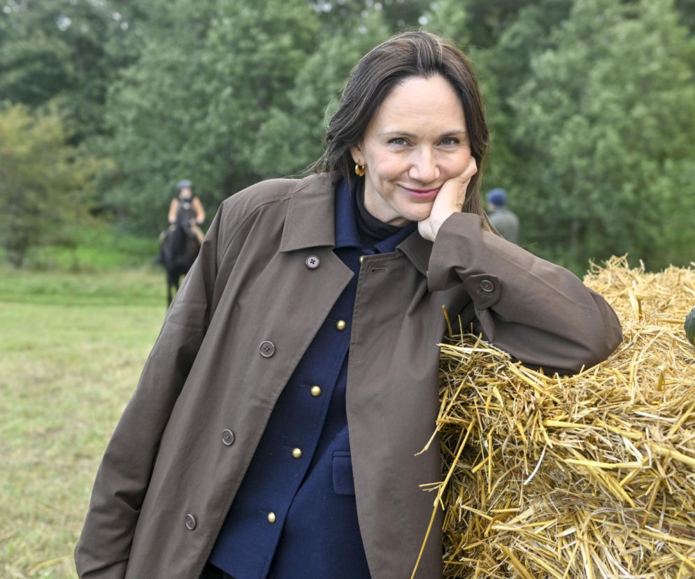 Aktorka Ilona Ostrowska uśmiecha się, opierając o belę słomy. O jej powrocie do roli Lucy w serialu Ranczo przeczytasz w SE.