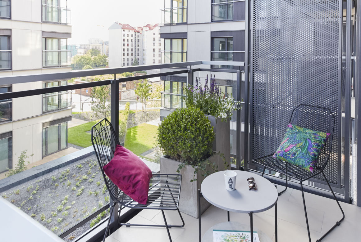 Mały balkon w bloku lub kamienicy z otwartym widokiem.