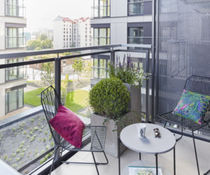 Mały balkon w bloku lub kamienicy z otwartym widokiem.