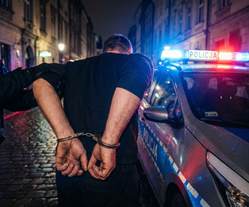 Ręce mężczyzny w kajdankach prowadzonego przez policjanta