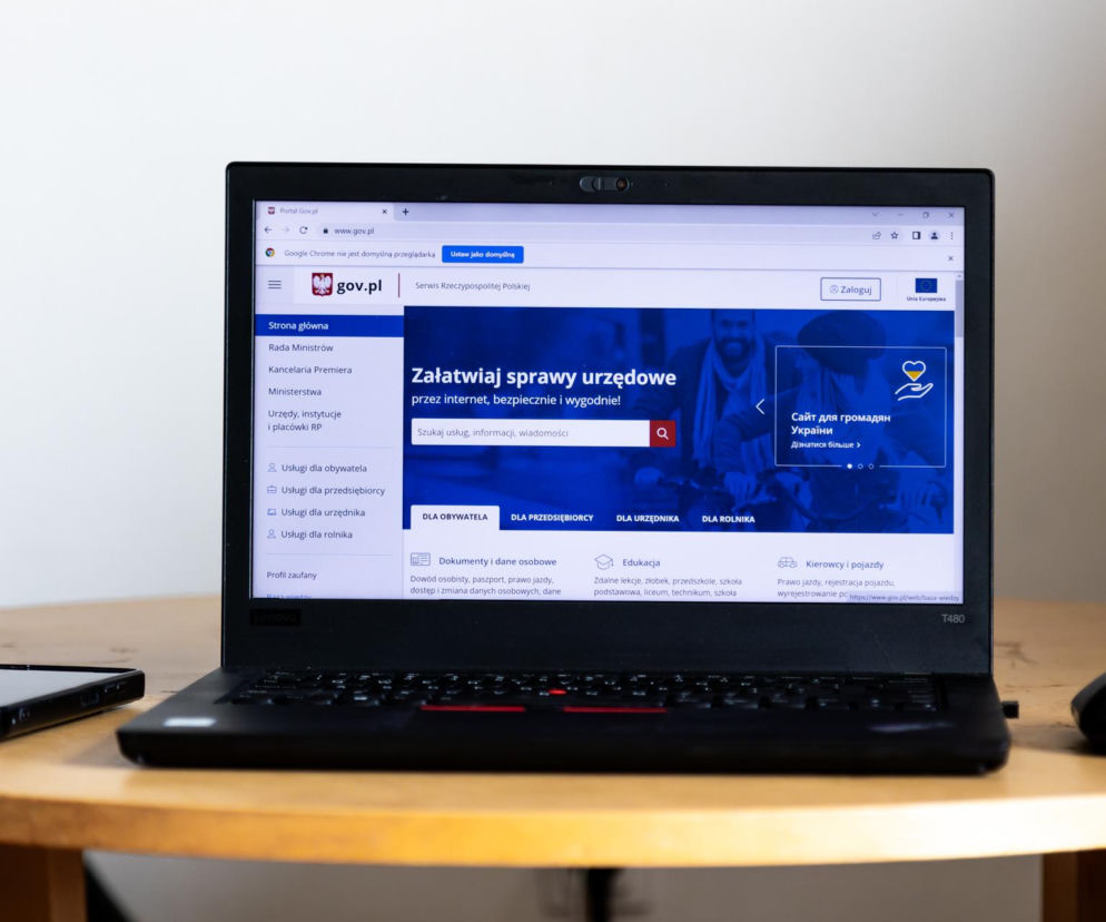 Otwarty laptop Lenovo wyświetlający stronę gov.pl, oferującą usługi Twój e-PIT dla przedsiębiorców, co jest tematem artykułu na Super Biznes. Obok leży smartfon i myszka komputerowa.