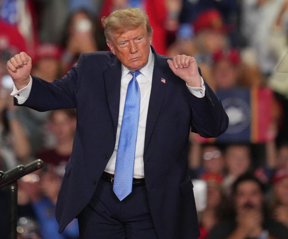Donald Trump w garniturze zaciska pięści na wiecu. O sondażach prezydenta USA przeczytasz na SE Polityka.