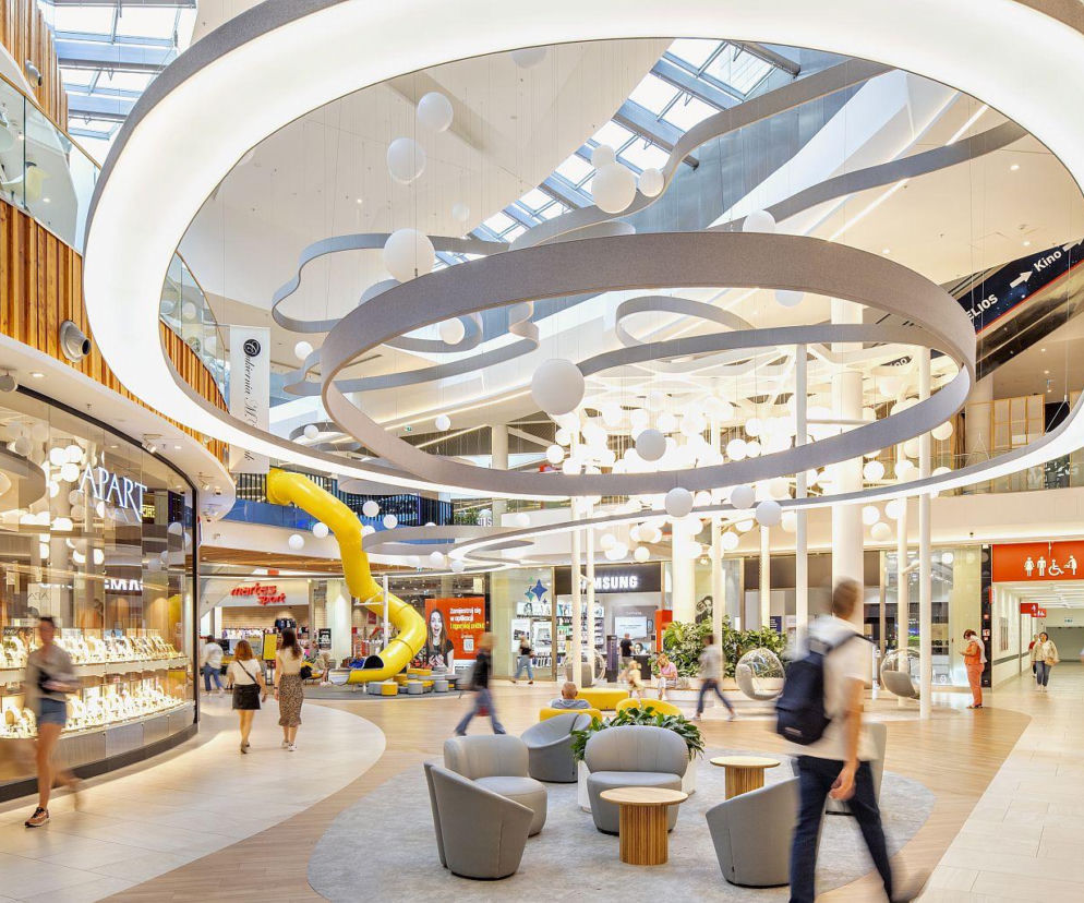 Nowoczesne wnętrze Alei Bielany we Wrocławiu z witrynami sklepów i strefą relaksu. O rozwoju centrum przeczytasz na SE.