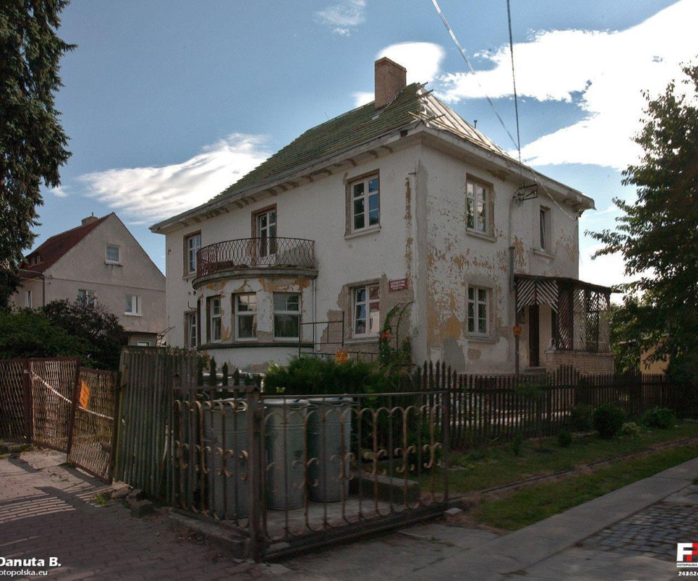 Zniszczony budynek dawnego pensjonatu w Opolnie-Zdroju, z opadającym tynkiem i zaniedbanym balkonem, symbolizuje zaniedbanie wsi zagrożonej działalnością kopalni Turów, o czym więcej przeczytasz na naszym portalu.