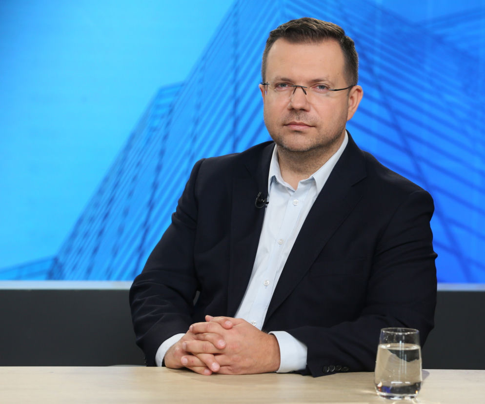 Przemysław Litwiniuk, członek RPP, w okularach, marynarce i białej koszuli, z dłońmi splecionymi na stole, podczas rozmowy w studiu Super Biznesu na temat inflacji i stóp procentowych.
