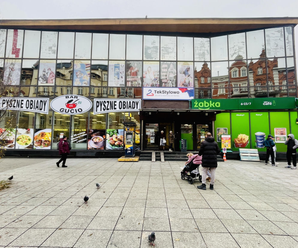 Zmodernizowany pawilon Domus w Katowicach, obecnie Ślązak, z przeszkloną fasadą i widocznymi szyldami Bar Gucio oraz Żabka, z przechodniami na placu. O historii i przyszłości tego obiektu przeczytasz na portalu Architektura Murator Plus.