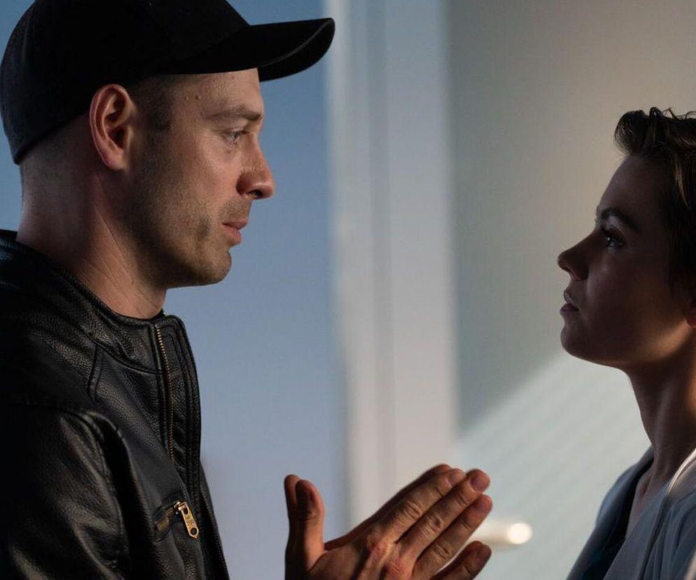 Mario (Marcin Korcz) w czarnej czapce i skórzanej kurtce, z rękoma złożonymi jak do modlitwy, spogląda na Blankę (Pola Gonciarz) w jasnej bluzce, o której nowym sezonie serialu Na dobre i na złe przeczytasz na Super Seriale.