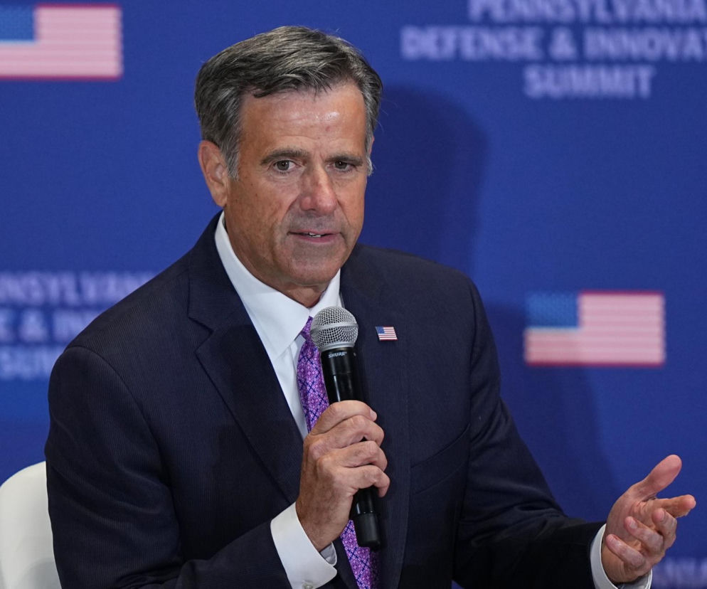 Dyrektor CIA John Ratcliffe przemawia do mikrofonu na tle flag USA. O jego misji w Moskwie przeczytasz na SE Polityka.