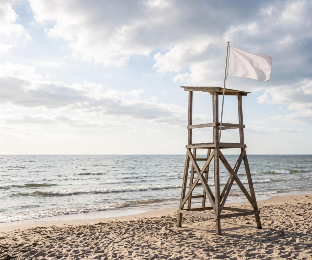 Drewniana wieża ratownika z białą flagą na plaży w Grzybowie. O bezpieczeństwie nad wodą przeczytasz na SE Szczecin.