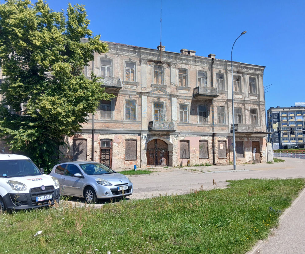 Zaniedbana, zabytkowa kamienica przy ul. Dąbrowskiego 14 w Białymstoku z wybitymi oknami i odpadającym tynkiem. Budynek otoczony jest zielenią i zaparkowanymi samochodami. Więcej o stanie zabytku przeczytasz na Architektura Murator Plus.