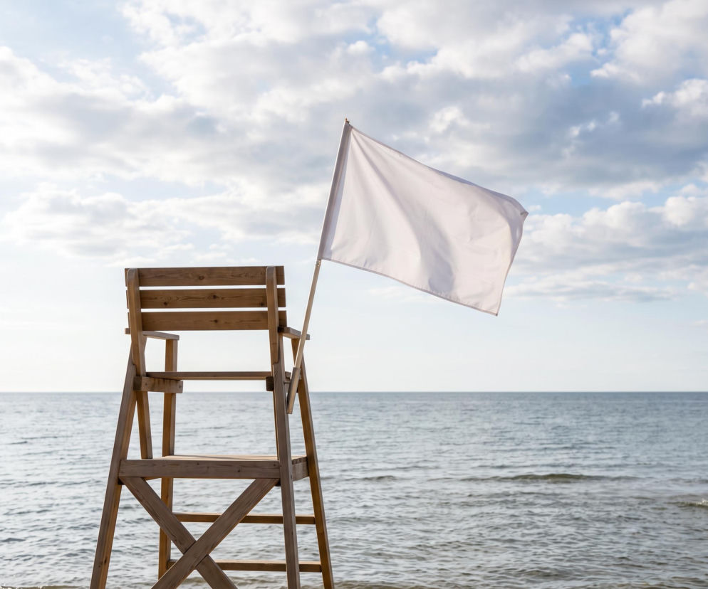 Drewniane krzesło ratownika z białą flagą na plaży w Świnoujściu. O warunkach nad morzem przeczytasz na SE Szczecin.
