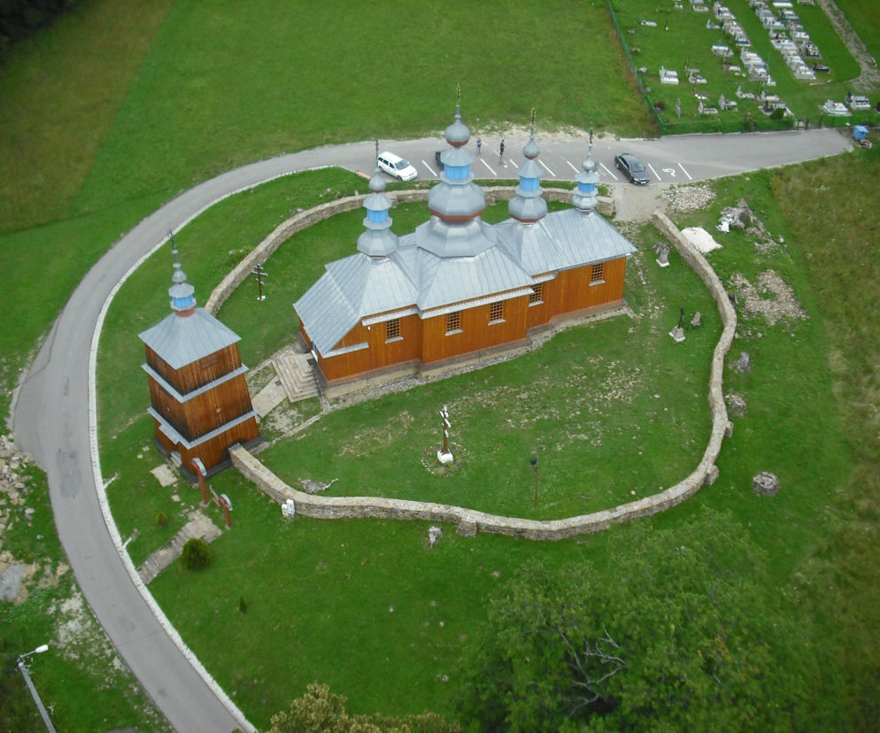 Cerkiew w Komańczy z lotu ptaka. Obok dzwonnica i mur. O odbudowie po pożarze przeczytasz na portalu Architektura.