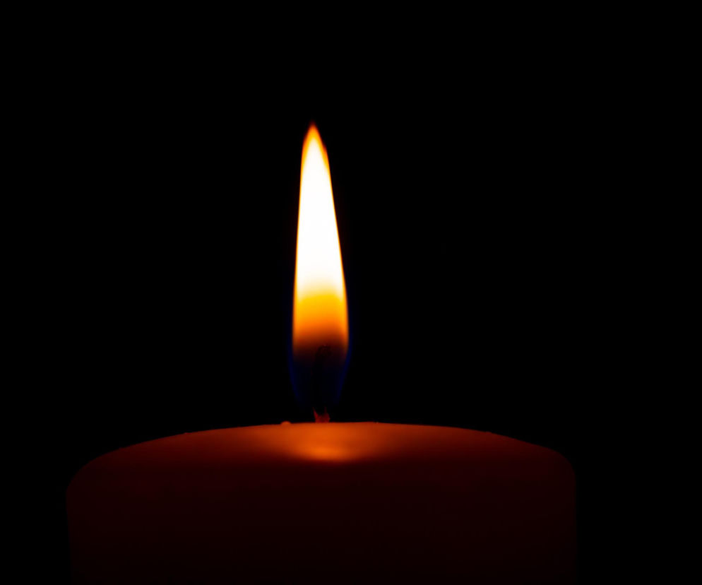 Płonąca świeca na czarnym tle, symbolizująca żałobę po śmierci żony Przemysława Babiarza. Blask ognia w ciemności ukazuje smutek i pamięć o zmarłej, której los dotknął dziennikarza i środowisko sportowe, o czym można przeczytać na portalu Poradnik Zdrowie.