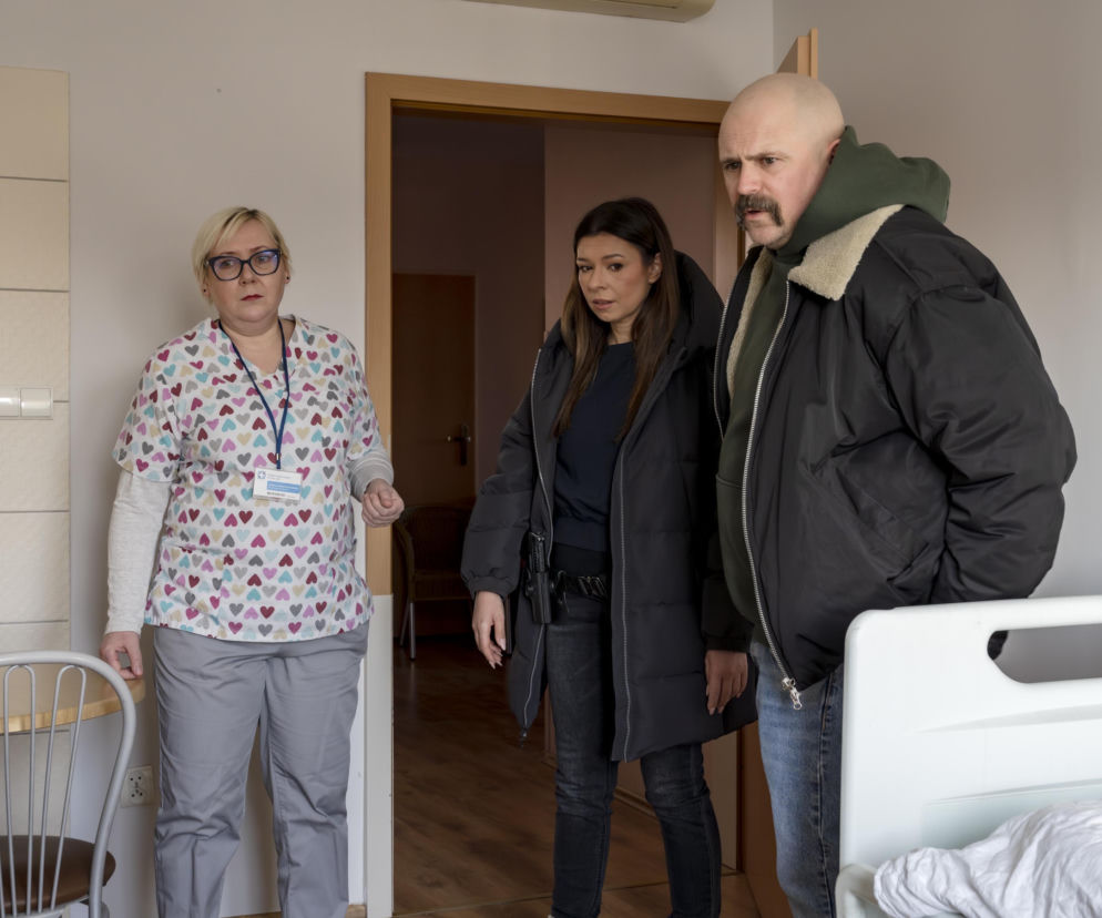 Pielęgniarka w stroju medycznym w serduszka rozmawia z policjantką i aspirantem Jakubem Walczakiem z serialu Sprawiedliwi – Wydział Kryminalny. Scena z odcinka 1011, gdzie śledczy zajmują się tajemnicą zatrutego alkoholu. Więcej o ich losach na Super Seriale.