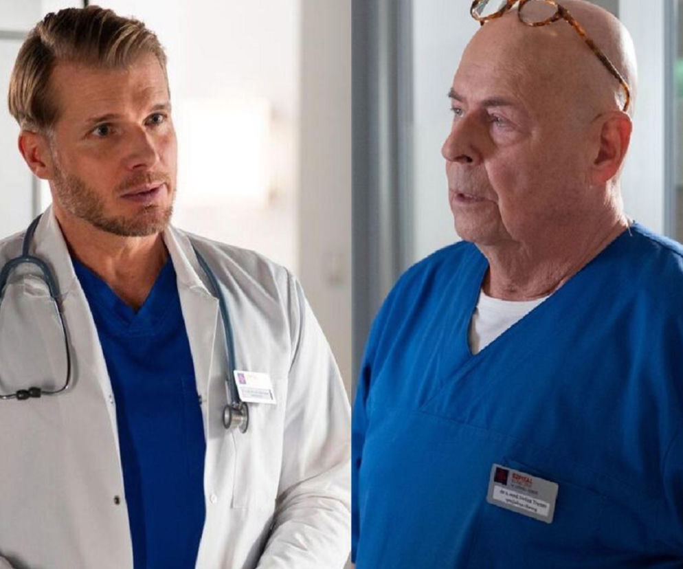 Lekarze Maks Beger (Tomasz Ciachorowski) i Stefan Tretter (Piotr Garlicki) z serialu Na dobre i na złe rozmawiają w szpitalu. Beger, ubrany w biały kitel i niebieski scrubs, patrzy na Trettera w niebieskim scrubsie. Zdjęcie ilustruje konflikt między bohaterami, o którym przeczytasz więcej na Super Seriale.