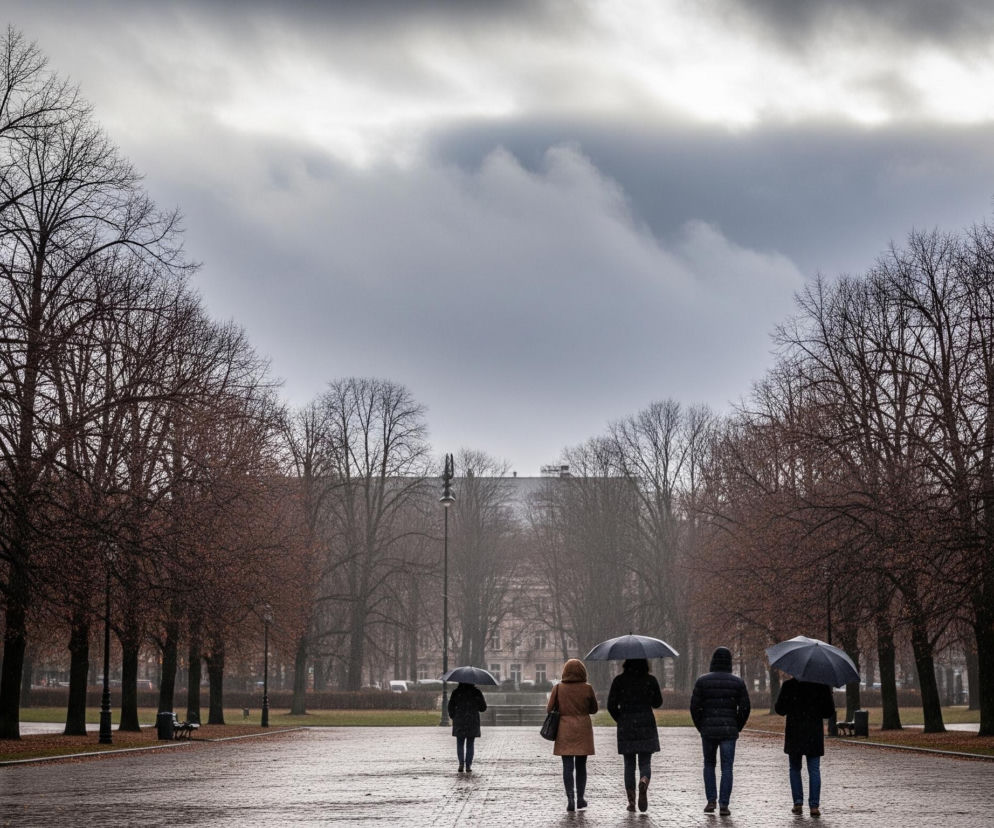 Pięć osób z parasolami idzie kamiennym chodnikiem, który rozciąga się w głąb obrazu, pod posępnym, zachmurzonym niebem. Po obu stronach chodnika rosną szeregi drzew o nagich, ciemnych gałęziach, niektóre z nich mają jeszcze pojedyncze, brązowe liście. W oddali, za drzewami, widać zarysy budynków i szarą, zamgloną przestrzeń. Całość utrzymana jest w chłodnych, stonowanych barwach.
