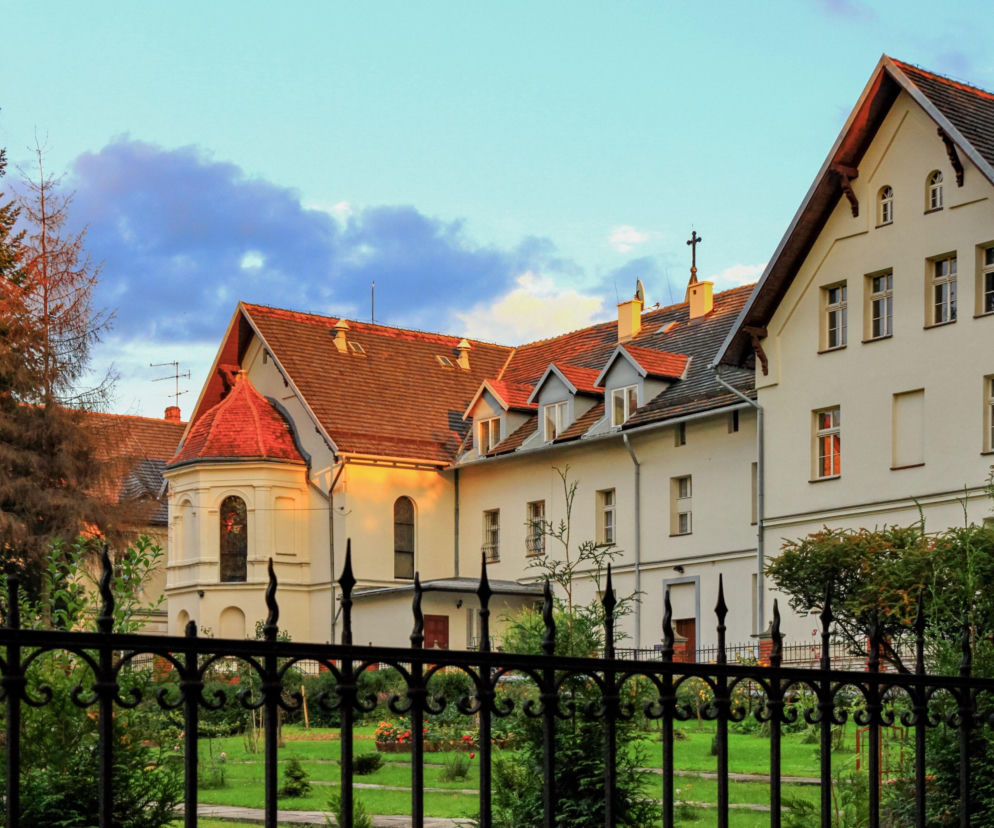 Zabytkowe budynki uzdrowiskowe w Jastrzębiu-Zdroju za ozdobnym płotem. O historii kurortu przeczytasz na Eska Śląskie.