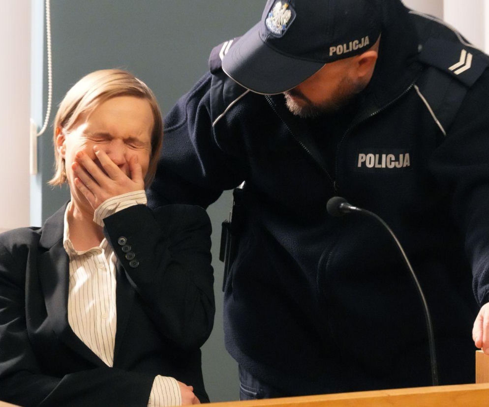 Weronika Nockowska jako Sonia z serialu Barwy szczęścia w scenie sądowej, zasłaniająca twarz dłonią w geście płaczu, w tle policjant. Więcej o losach Soni na portalu Super Seriale.