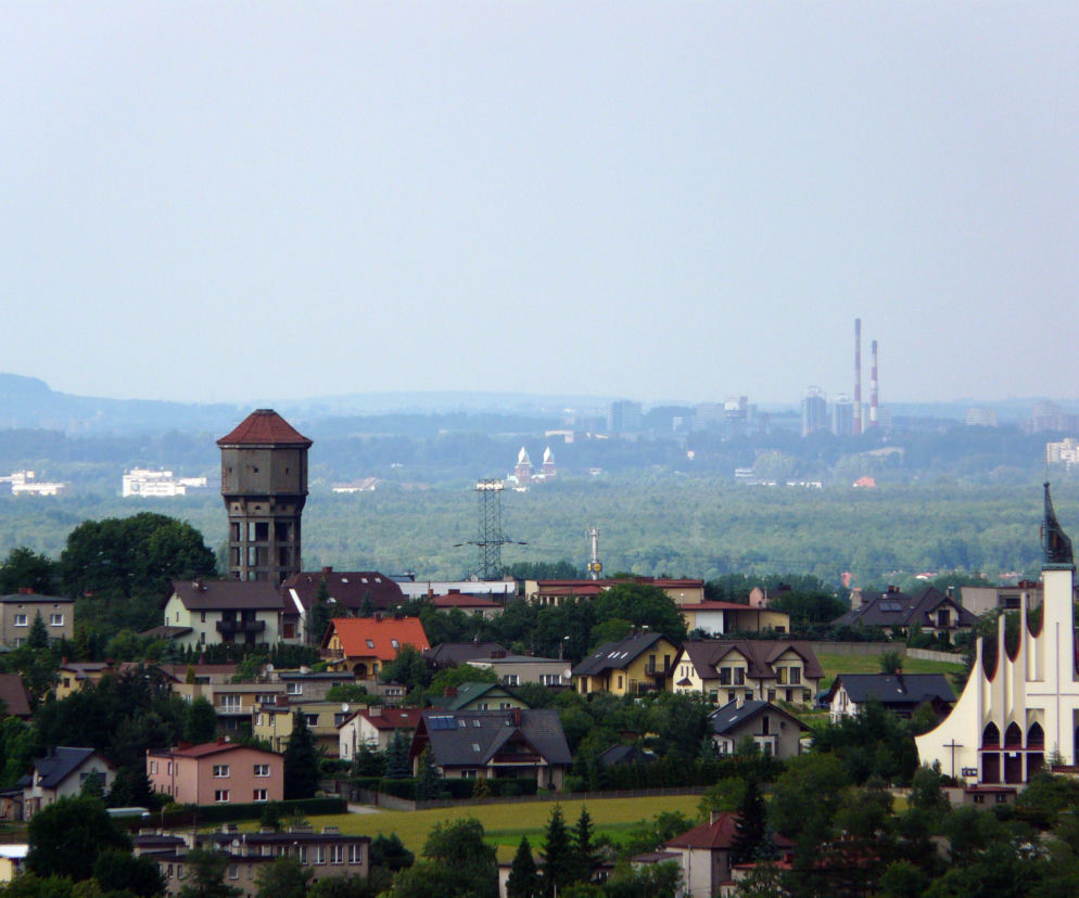 Panorama Łazisk Górnych z widoczną wieżą ciśnień, kościołem i kominami przemysłowymi. O mieście czytaj na Eska Śląskie.