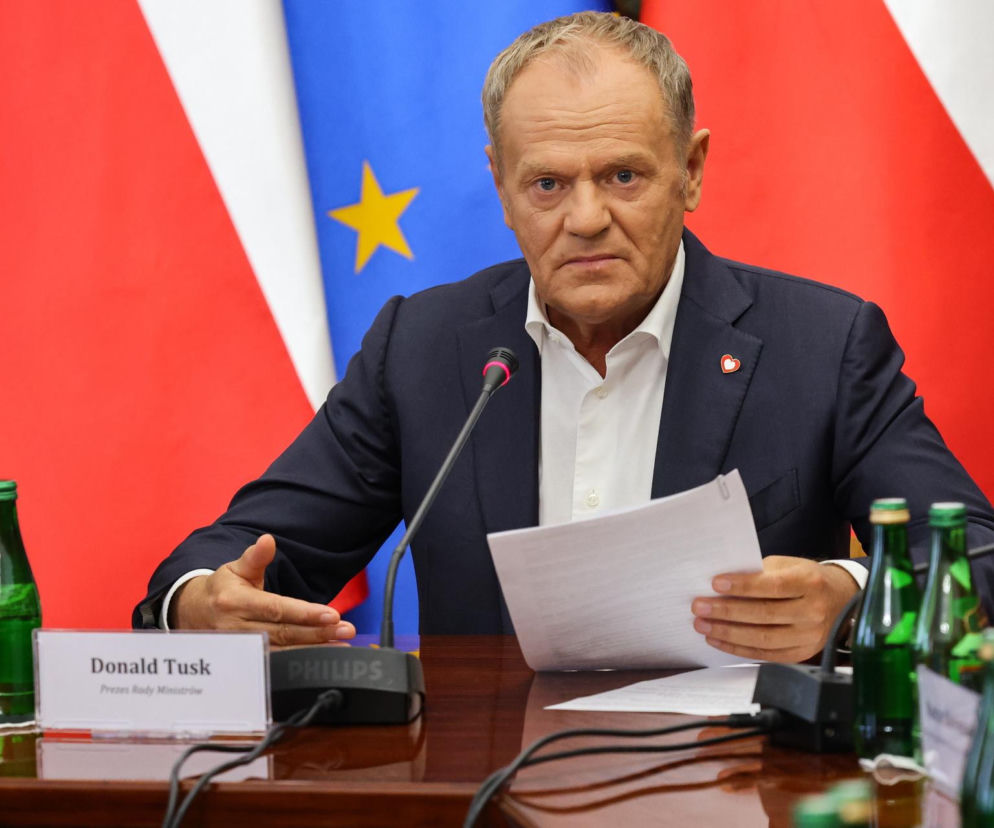 Premier Donald Tusk trzymający dokumenty przy stole obrad. O walce z mową nienawiści przeczytasz na SE Polityka.