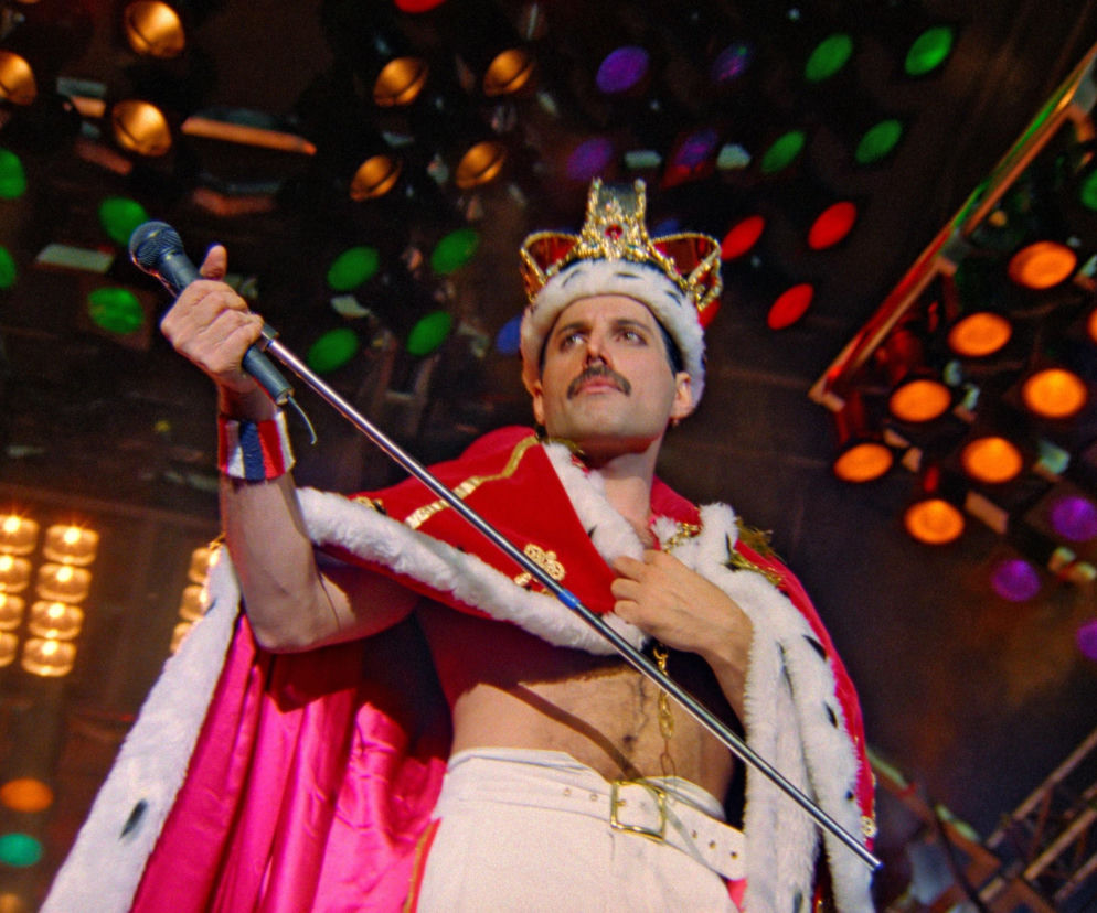 Freddie Mercury w koronie i królewskim płaszczu na scenie. O sukcesie utworu Queen przeczytasz na EskaRock.