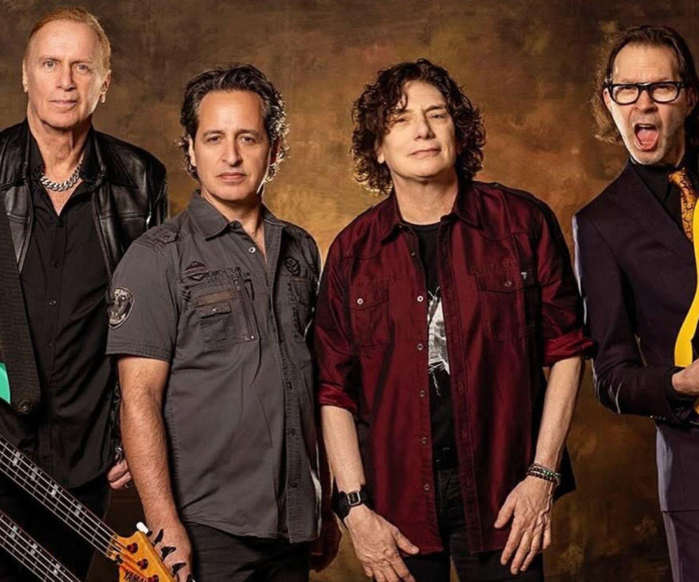 Muzycy zespołu Mr. Big pozują z gitarami na brązowym tle. O historii grupy i nurcie grunge przeczytasz na EskaRock.