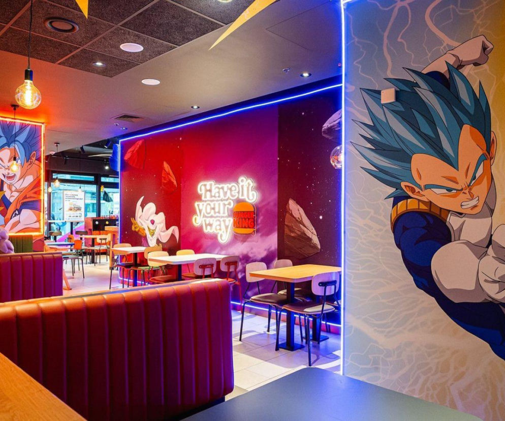 Wnętrze Burger Kinga w stylu Dragon Ball Super z postaciami Goku i Vegety na ścianach. Szczegóły akcji znajdziesz na Eska.