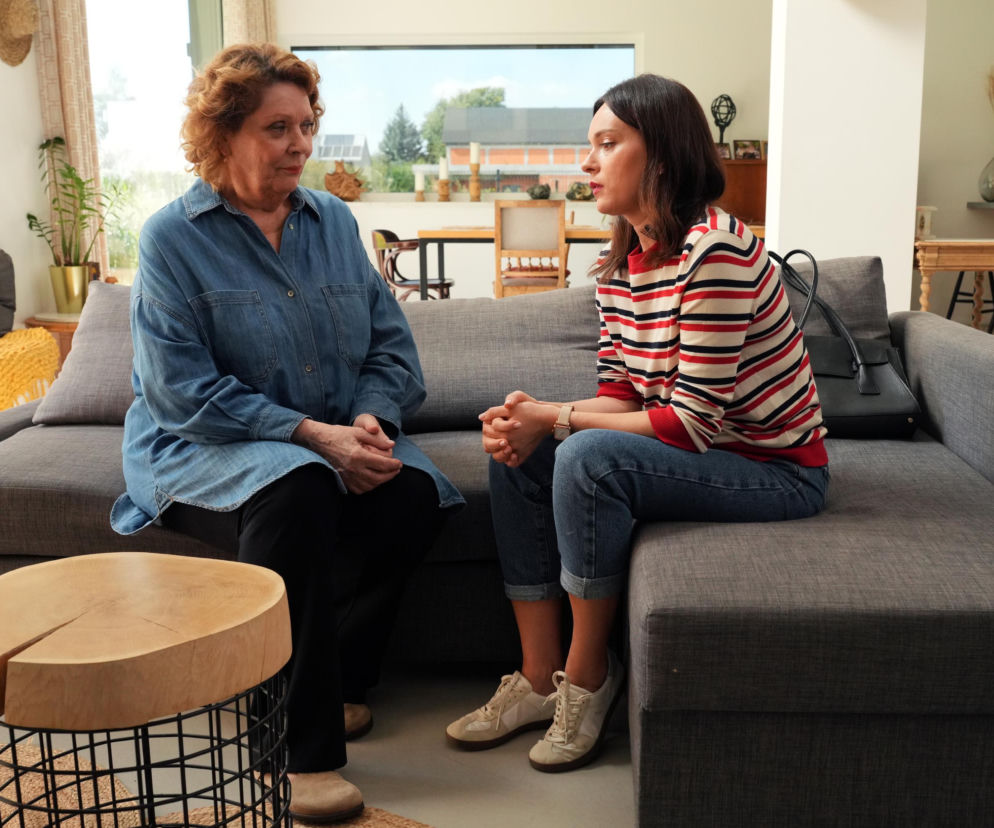 Natalia (Maria Dejmek) i Józefina (Elżbieta Jarosik) siedzące na szarej kanapie w domu. Józefina, w denimowej koszuli, z zakłopotaną miną patrzy na Natalię, która w pasiastym swetrze i jeansach, ze złożonymi dłońmi, ze smutkiem opowiada o swoim małżeństwie. Obie kobiety są bohaterkami serialu Barwy szczęścia, a o ich losach dowiesz się więcej na portalu Super Seriale.