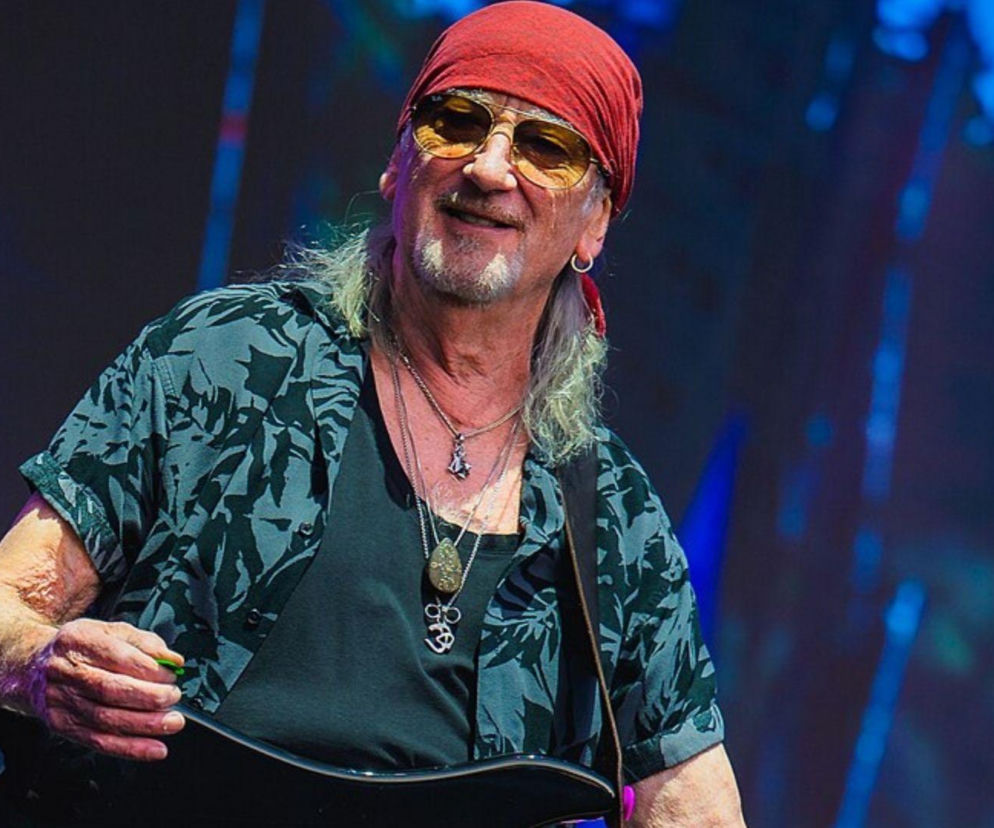Uśmiechnięty Roger Glover z Deep Purple w czerwonej chustce na scenie. O koncertach w Polsce przeczytasz na EskaRock.