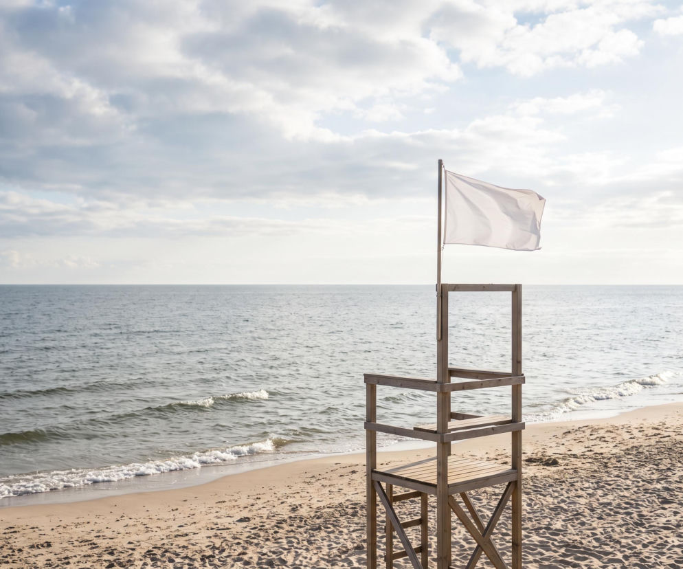Drewniana wieża ratownicza z białą flagą na plaży w Jastrzębiej Górze. O warunkach kąpieli pisze Eska Trójmiasto.