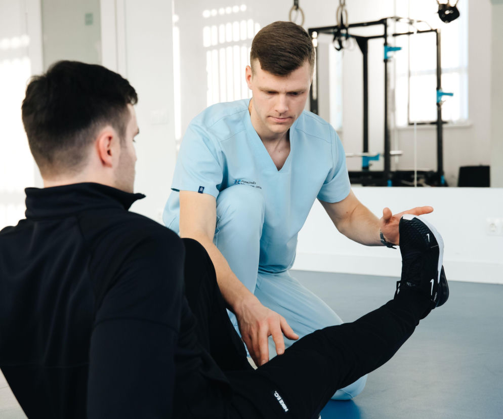 Fizjoterapeuta rozciąga nogę pacjenta. O nowoczesnej rehabilitacji reumatologicznej przeczytasz na Poradnik Zdrowie.